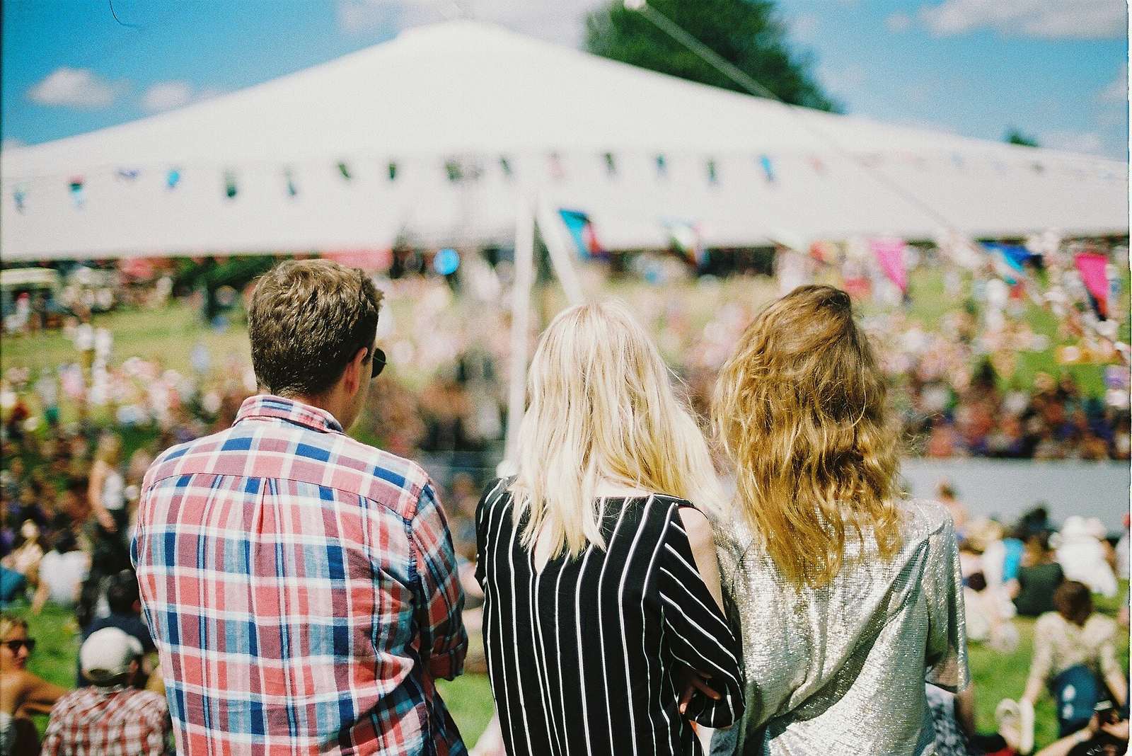 Festival-goers gathered in front of a white marquee on a sunny day